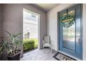 Charming front porch with a gray chair, potted plant, welcome mat, and a blue front door with wreath at 4652 San Martino Dr, Wesley Chapel, FL 33543