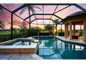 A luxurious screened-in pool and spa area offer serene outdoor living with a picturesque sunset view at 984 Chickadee Dr, Venice, FL 34285