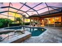 A luxurious screened-in pool and spa area offer serene outdoor living with a picturesque sunset view at 984 Chickadee Dr, Venice, FL 34285