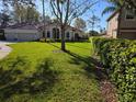 Landscaped front yard with a well-maintained lawn and mature hedges and trees at 9127 Woodridge Run Dr, Tampa, FL 33647