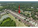 An aerial view of a neighborhood featuring single Gathering homes, mature trees, and a community lake at 26501 Whirlaway Ter, Wesley Chapel, FL 33544