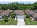Aerial view of a single-Gathering home with a well-manicured lawn, two-car garage and mature trees at 26501 Whirlaway Ter, Wesley Chapel, FL 33544