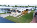 Bright mobile home with landscaped lawn, featuring a covered porch and accessible ramp at 37105 Lois Ave, Zephyrhills, FL 33542
