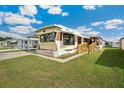 Cozy mobile home with well-kept lawn and wooden access ramp, ideal for comfortable living at 37105 Lois Ave, Zephyrhills, FL 33542