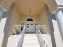 Inviting front porch with double doors, white railing and columns, and elegant lighting at 5025 Westshore Dr, New Port Richey, FL 34652