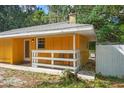 Side view of a yellow home with a white railing porch, chairs and mature trees at 8828 Jasmine Blvd, Port Richey, FL 34668