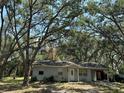 Charming single-story home featuring a quaint front porch and lush, mature trees surrounding the property at 12720 Jan St, San Antonio, FL 33576