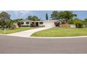Well-maintained single-story home with a white exterior, manicured lawn, and mature landscaping at 1322 Byron Dr, Clearwater, FL 33756