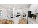 Bright modern kitchen with white cabinetry, stainless steel appliances, pendant lighting and wood flooring at 3404 Lumber Falls Dr, Plant City, FL 33565