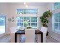 Inviting dining area with view to the pool features a modern table, white chairs, and large windows at 35 Deerpath Dr, Oldsmar, FL 34677