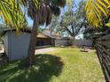 Spacious backyard with green grass, mature trees, and a partial view of a screened-in lanai at 484 Itasca Ave, Tampa, FL 33606