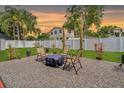 Relaxing backyard patio with chairs, a fire pit, stone ground cover, and manicured green grass at 6471 109Th N Ter, Pinellas Park, FL 33782