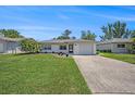 Inviting single-story home with lush lawn, garden, and an attached one-car garage at 6520 Meadowbrook Ln, New Port Richey, FL 34653