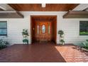 Inviting front entrance with a wood-stained porch and a decorative glass front door at 8011 N Mobley Rd, Odessa, FL 33556