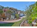 Landscaped front yard with brick-paved walkway, flowerbeds, and mature trees leading to the house at 8916 Southbay Dr, Tampa, FL 33615