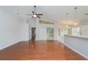 Bright living room featuring gleaming hardwood floors, a ceiling fan, and a kitchen view at 11741 Teapot Ct, Spring Hill, FL 34609