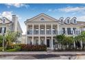 Inviting townhome showcasing a welcoming porch, white columns, dark trim and manicured landscaping at 135 Commonwealth N Ct, St Petersburg, FL 33716
