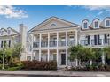 Two-story townhome with white columns, front porch, and dark accents, set amidst lush, manicured landscaping at 135 Commonwealth N Ct, St Petersburg, FL 33716