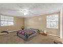 Spacious bedroom featuring neutral walls, carpeted flooring, a ceiling fan, and natural light from two windows at 1506 E Poinsettia Ave, Tampa, FL 33612