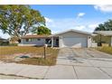 Inviting single-story home with an attached garage and classic landscaping under a clear blue sky at 1700 Ironwood E Ct, Oldsmar, FL 34677
