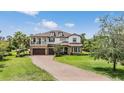 Elegant two-story home with three-car garage, stone accents, balcony and manicured lawn at 17724 Daisy Farm Dr, Lutz, FL 33559