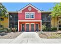 Charming two-story condo with a colorful red exterior, screened-in balconies, and well-maintained landscaping at 5705 Baywater Dr # 5705, Tampa, FL 33615