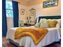 Warm bedroom features a large bed with patterned pillows, gold accents, and cozy blue curtains at 6741 4Th Ave N, St Petersburg, FL 33710