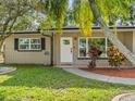 Inviting front entrance featuring a white door, lush landscaping, and a charming pathway at 7137 Wedgewood Dr, New Port Richey, FL 34652