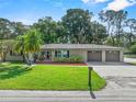 Charming single-story home featuring lush green lawn, mature trees, complemented by a double car garage at 7137 Wedgewood Dr, New Port Richey, FL 34652