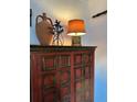 Beautiful rustic red and gold cabinet with decorative lamp and vase on top at 1020 38Th N Ave, St Petersburg, FL 33704