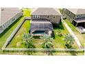 Aerial view of backyard featuring a screened-in pool, well-kept lawn, and a classic white picket fence at 13111 Bahia Grass Ln, Riverview, FL 33579