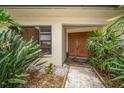 Elegant front entrance with double doors, surrounded by tropical plants and decorative landscaping at 14175 Feather Sound Dr, Clearwater, FL 33762