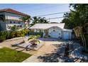 Aerial view of a cute home with white exterior, a metal roof, lovely tropical landscaping, and a large driveway at 1857 Bayou Grande Ne Blvd, St Petersburg, FL 33703