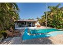 Inviting backyard with a turquoise pool, screened enclosure, comfortable lounge chairs, and lush tropical landscaping at 1857 Bayou Grande Ne Blvd, St Petersburg, FL 33703