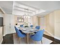 Formal dining area featuring a marble-top table with six blue chairs and stylish light fixture at 3211 W Swann Ave # 605, Tampa, FL 33609