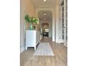 Bright hallway with wood-look tile flooring, arched entryway, and elegant wainscoting details at 3952 Aldea Way, Wesley Chapel, FL 33543