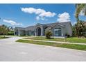 Charming single-story home with manicured lawn, complementing the gray exterior and stone paver driveway at 4012 Wellington Pkwy, Palm Harbor, FL 34685