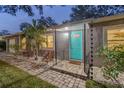 Inviting front entrance with a bright turquoise door, stone pathway, and manicured landscaping at 4324 S Clark Ave, Tampa, FL 33611