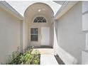 Charming home entrance with decorative arch, white door, and manicured plants at 4921 Wessex Way, Land O Lakes, FL 34638