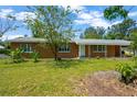 Inviting single-story home with a classic brick facade, mature trees, and a lush green lawn at 6104 Palm Ave, Gibsonton, FL 33534