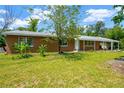 Well-kept brick single-story house with mature landscaping and a long covered carport on a sunny day at 6104 Palm Ave, Gibsonton, FL 33534