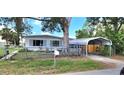 Cozy single-story home with a front yard, car port, and mature trees at 6825 Hammock Rd, Port Richey, FL 34668