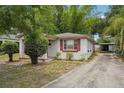 Cozy single-story home featuring a driveway leading to a detached carport, and red shutters at 7511 N Ola Ave, Tampa, FL 33604