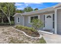 Close-up view of home's entrance, highlighting the front door, window, and manicured flower bed at 106 Avery Ave, Crystal Beach, FL 34681