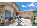 Close up of a charming front courtyard featuring a decorative fountain and lush landscaping at 11974 Rosetree S Pl, Seminole, FL 33772