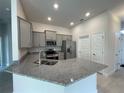 Well-equipped kitchen with granite countertops, stainless steel appliances, tile flooring, and gray cabinetry at 13187 Ogden Glade Rd, Dade City, FL 33525