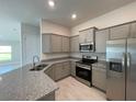 Modern kitchen featuring gray cabinets, granite countertops, stainless steel appliances and tile flooring at 13187 Ogden Glade Rd, Dade City, FL 33525