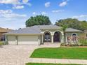 Charming single-story home with a three-car garage, manicured lawn, and inviting brick-paved driveway at 1521 Brittany Ct, New Port Richey, FL 34655