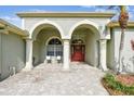 Inviting front porch with stately columns, arched entryways, and brick-paved sitting area at 1521 Brittany Ct, New Port Richey, FL 34655
