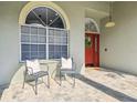 Inviting front porch with a welcoming red door, brick-paved floor, and comfortable seating at 1521 Brittany Ct, New Port Richey, FL 34655